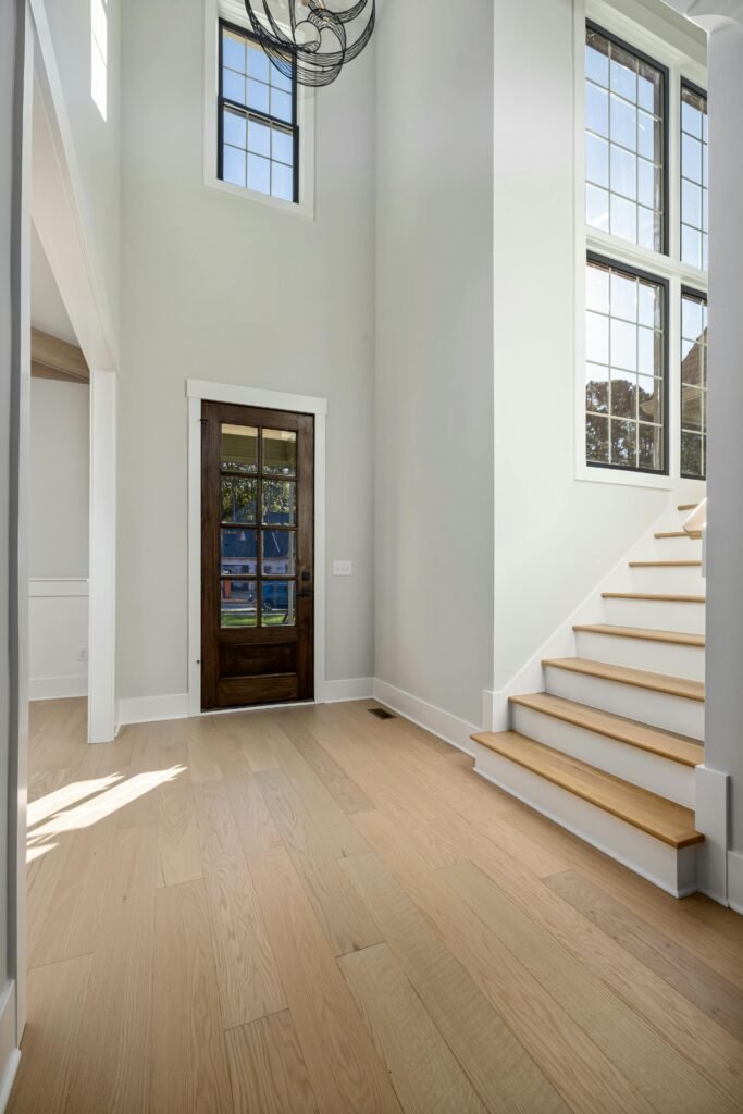 Bright and spacious home entryway featuring wooden flooring and large windows.