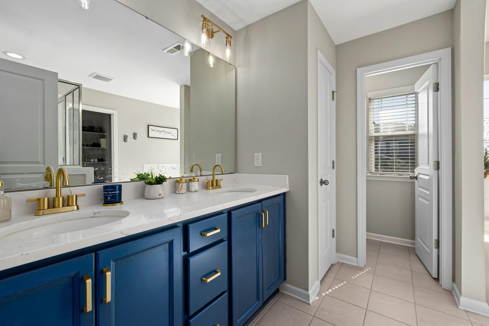 Stylish bathroom featuring a blue vanity, gold fixtures, and decorative accents for a modern home interior.