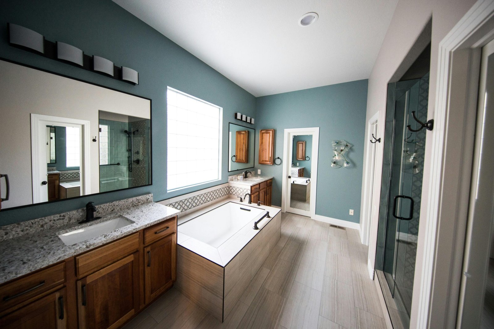 Spacious modern bathroom featuring a freestanding bathtub, wooden cabinets, and granite countertops.